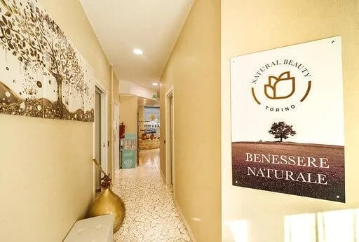 Interior hallway of a wellness spa with beige walls, terrazzo flooring, and a signage reading Benessere Naturale.